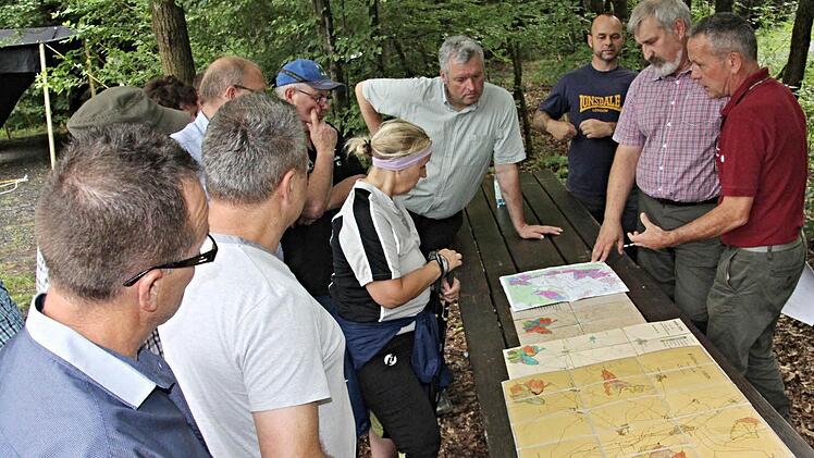 Vor dem Waldgang gab es durch die beiden Forstbeamten Wolfgang Gnannt und Jürgen Hahn (von rechts) anhand von Kartenmaterial Informationen über das Waldgebiet Wüstenhof. Bürgermeister Jürgen Hennemann (hinten Mitte) ist aufmerksam bei der Sache. Foto: Helmut Will
