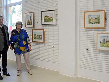 Albrecht Morgenroth (Vorsitzender der Stiftung Judenbach) mit Helga Barop vor einigen Aquarell- Exponaten der Sonnefelder Künstlerin. Unter anderem sind die Veste Coburg, das Wasserschloss Mitwitz und die Festung Rosenberg Kronach zu sehen.  Foto: K.- H. Hofmann