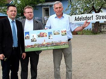 Bald wird in der ugandischen Gemeinde Massaka eine Straße nach Adelsdorf benannt. Symbolisch hat Bürgermeister Karsten Fischkal (links) beim Pfarrfest das "Adelsdorf-Street"-Schild an Kirchenpfleger Günther Müller, der bald nach Uganda fliegt, übergeben - in der Mitte Pfarrer Thomas Ringer. Fotos: Johanna Blum