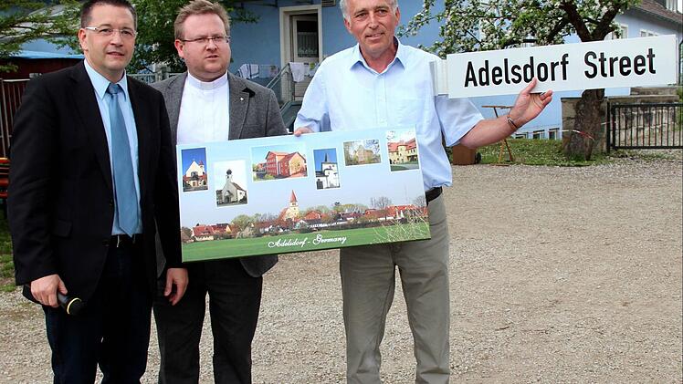 Bald wird in der ugandischen Gemeinde Massaka eine Straße nach Adelsdorf benannt. Symbolisch hat Bürgermeister Karsten Fischkal (links) beim Pfarrfest das "Adelsdorf-Street"-Schild an Kirchenpfleger Günther Müller, der bald nach Uganda fliegt, übergeben - in der Mitte Pfarrer Thomas Ringer. Fotos: Johanna Blum