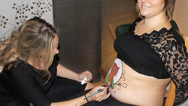 Alexandra Lamm bei der Arbeit in ihrem kleinen Atelier in Unterschleichach. Etwa eineinhalb Stunden dauert die Bemalung eines Babybauchs. Nadine hat sich eine Eule als Motiv ausgesucht.  Foto: Katja Müller
