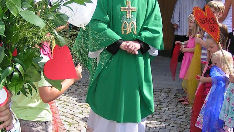Pfarrer Gerhard Möckel wird von den Kindergartenkindern vor dem Kirchenportal empfangen. Foto: Heidi Amon