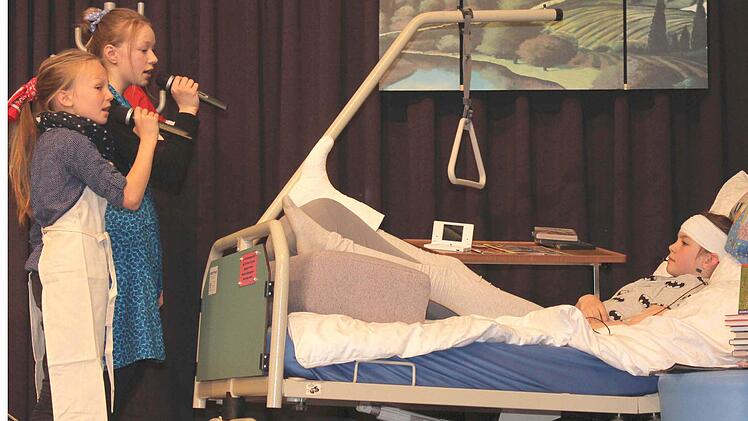 Die Putzfrauen, gespielt von Anna Kunkel und Annabell Schneider, lesen (bzw. singen) Timo (Elena Bahrt) in seinem Krankenbett die Leviten, wegen der ewigen Stöpsel im Ohr. Fotos: Ralf Naumann