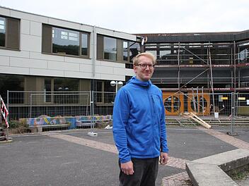 Peter Karl vom städtischen Baubüro auf dem Pausenhof: Links ist die generalsanierte Mittelschule gut erkennbar, im rechten Teil des Schulgebäudes laufen die Arbeiten derzeit an. Foto: Ulrike Müller