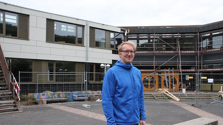 Peter Karl vom städtischen Baubüro auf dem Pausenhof: Links ist die generalsanierte Mittelschule gut erkennbar, im rechten Teil des Schulgebäudes laufen die Arbeiten derzeit an. Foto: Ulrike Müller