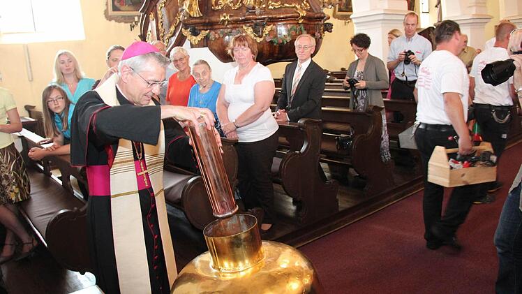 Erzbischof Ludwig Schick steckt die Bulle in die Turmkugel. Fotos: Johanna Blum