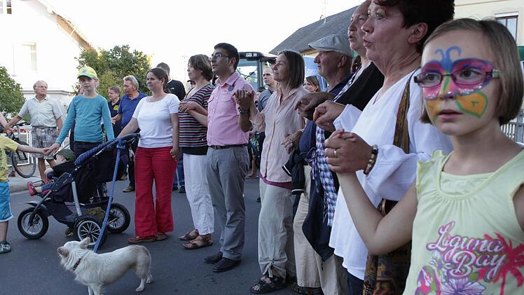 Nach dem multireligiösen Friedensgebet nahmen sich die Teilnehmer an der Protestkundgebung der Bürgerinitiative "Schwarzach ist bunt" an die Hand. Fotos: Barbara Herbst