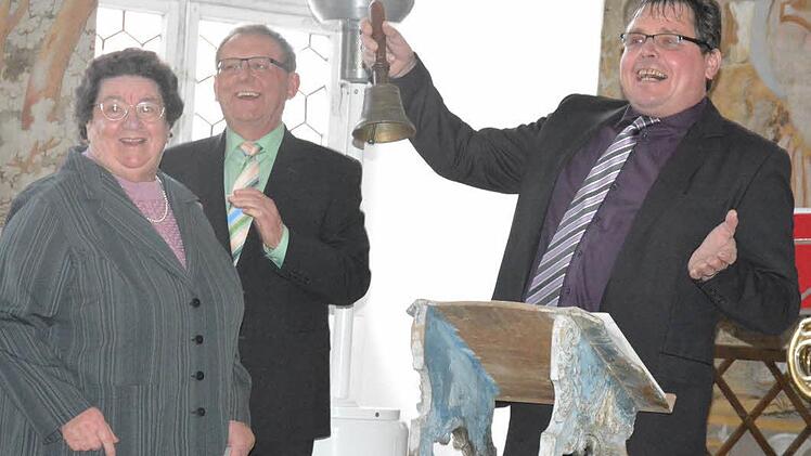 Sichtlich erfreut nimmt Bürgermeister Hermann Niediek (rechts) die Üschersdorfer Gemeindeglocke von Hildegard Nicklaus (links) in Empfang. Dahinter Zweiter Bürgermeister Günther Stottele. Foto: Gerhard Schmidt