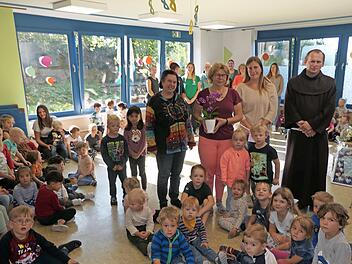 Unser Bild zeigt Leiterin Michaela Stark, Silvia Turbanisch, die stellvertretende Vorsitzende des Caritas Kindergartenvereins Ann-Kathrin Gradel und Pfarrer Pater Florian im Kreise der Elefantengruppe und dem ganzen Team im Hintergrund.