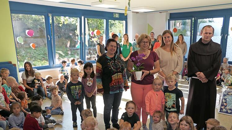 Unser Bild zeigt Leiterin Michaela Stark, Silvia Turbanisch, die stellvertretende Vorsitzende des Caritas Kindergartenvereins Ann-Kathrin Gradel und Pfarrer Pater Florian im Kreise der Elefantengruppe und dem ganzen Team im Hintergrund.