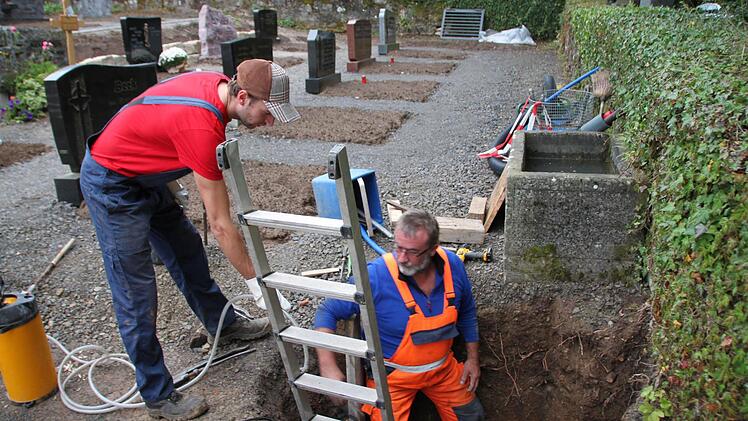 Wasserwart Bernhard Röß erneuerte die Wasserleitung am Friedhof in Burghausen; Ferienjobber Simon Bangert ging ihm zur Hand ging. Foto: Heike Beudert