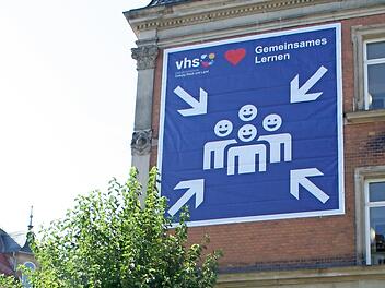Das Logo-Banner am Haus der Volkshochschule in der Löwenstraße 16 zeigt: Die Kurse gehen wieder los, und möglichst alle sollten zusammen lernen können.
