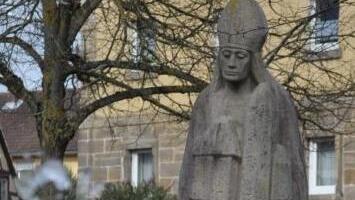 Vor der Statue des hl. Kilian auf dem Dorfplatz plätschert das Wasser aus einem Findling.