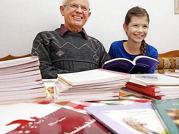 Alfons Genzler und Enkelin Chantal-Sophie Genzler blättern sich durch den Bücherstapel. Foto: Arkadius Guzy
