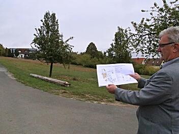 Bürgermeister Helmut Dietz mit dem ursprünglichen Plan für das Bebauungsgebiet vor dem Bebauungsgebiet. Auf der Wiese rechts des Weges sollen in abgespeckter Form noch vier Bauplätze entstehen. Weitere drei sind in Ortsnähe vorhanden. Helmut Will