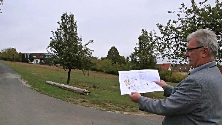 Bürgermeister Helmut Dietz mit dem ursprünglichen Plan für das Bebauungsgebiet vor dem Bebauungsgebiet. Auf der Wiese rechts des Weges sollen in abgespeckter Form noch vier Bauplätze entstehen. Weitere drei sind in Ortsnähe vorhanden. Helmut Will