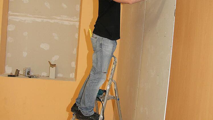 Markus Hörteis (30) sorgt dafür, dass die Holzverkleidung an der Außenwand hinter Rigips verschwindet.