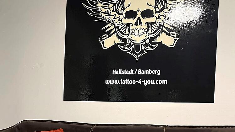 Ein gemütliches Wartebereich im Tattoo-Studio "Tattoo 4 you" mit einem Sofa, Snacks auf einem Tisch und einem Schädel-Logo an der Wand. Standort: Hallstadt/Bamberg.