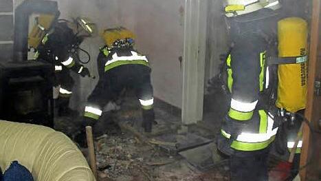 Pressiger Feuerwehrleute am Brandherd im Turmzimmer der Villa. Der so genannte "Fehlboden" wird aufgehackt, um an den Brandherd zu kommen.  Foto: Schedel