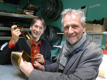 Das gibt's noch?! Bruno Schneyer (rechts) hält im Vorführraum der "Schauburg" von Clemens Scherer einen 70-Millimeter-Kinofilm in der Hand. Die "Schauburg" verfügt noch über einen voll funktionsfähigen Projektor. Foto: Kino-Schneyer