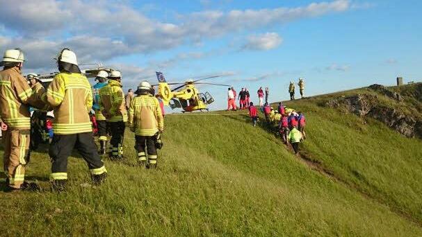 Helfer bringen den verunglückten Gleitschirmflieger zum Rettungshubschrauber.