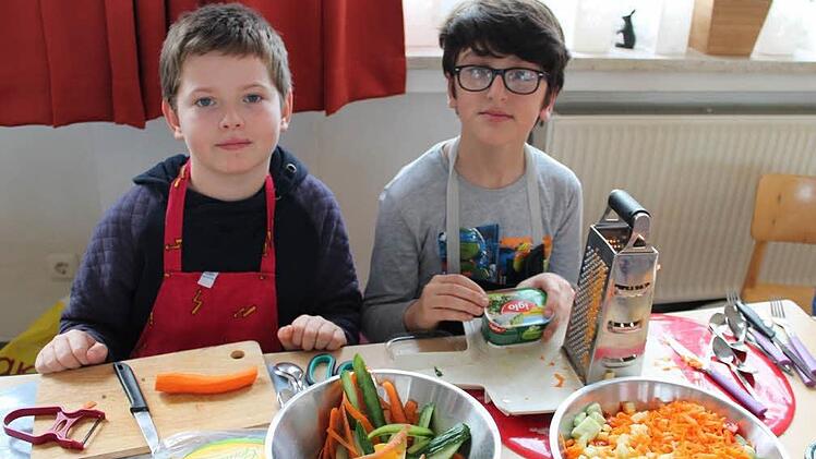 Max (links) und Sarmad bereiten gemeinsam eifrig einen kunterbunten Nudelsalat vor.