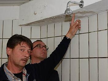 Stefan Metz (links), einer der drei Vorsitzenden des TSV Aschach, und Andreas Sandwall begutachten die Gästedusche in der Zehnthalle. Die sollen bald umfangreich renoviert werden. Foto: Björn Hein