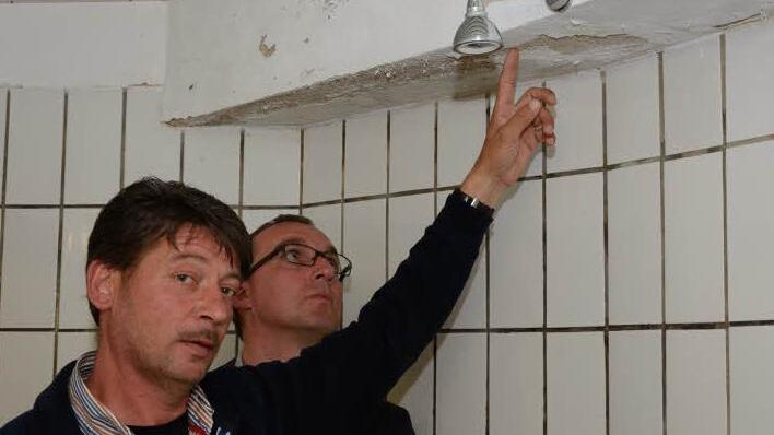 Stefan Metz (links), einer der drei Vorsitzenden des TSV Aschach, und Andreas Sandwall begutachten die Gästedusche in der Zehnthalle. Die sollen bald umfangreich renoviert werden. Foto: Björn Hein