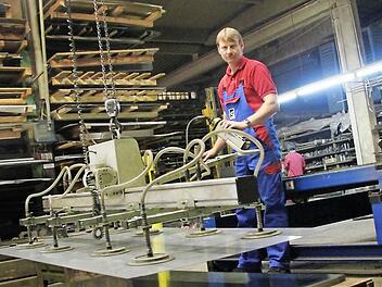 Mitarbeiter Alexander Schwan hebt eine Metallplatte vom Stapel, um diese im Laser zuschneiden zu lassen. Fotos: Thomas Heuchling