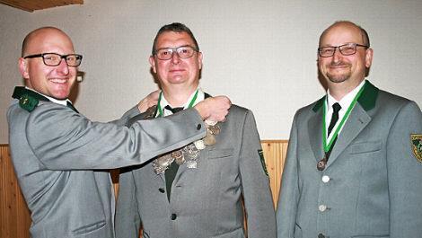 Frank Hillenbrand legt Manfred Bauer das Zeichen der Königswürde um, rechts daneben ist Erster Ritter Dieter Schmitt.  Foto: Gabriele Sell
