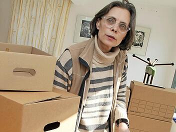 Mia Hochrein beim Verpacken ihrer Installation "Speicher" mit gestapelten Kartons und Sammelinhalten.