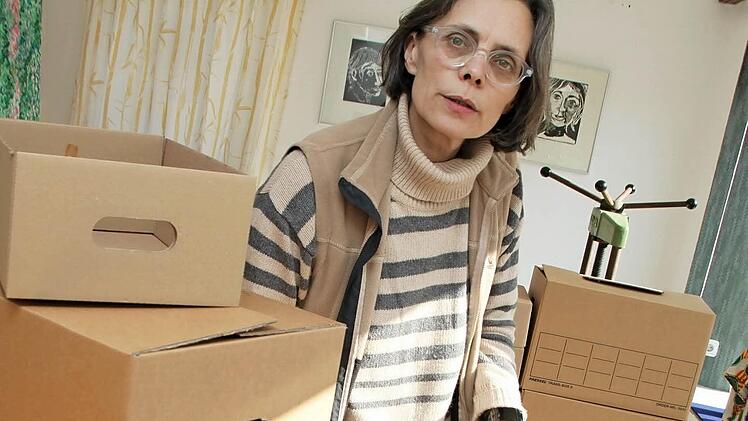 Mia Hochrein beim Verpacken ihrer Installation "Speicher" mit gestapelten Kartons und Sammelinhalten.