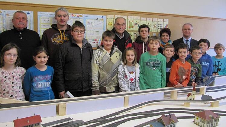In der Werkstatt steht bereits der  Unterbau für die meterlange Modelleisenbahnanlage. Nun dürfen die Viertklässer (hier mit Eltern, Großvätern und einem der Sponsoren)  basteln, kleben und modellieren. Foto:  M. Schütz
