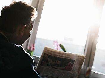 Herr Schmidt, der eigentlich anders heißt, liest den Sportteil einer Zeitung. Auf der Fensterbank im Zimmer des krebskranken Mannes stehen Blumen, die für ein Gefühl von Wärme und Heimat sorgen sollen.  Foto: Hendrik Steffens