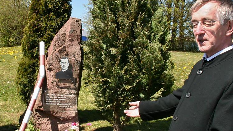 Der Postulator des Seligsprechungsverfahrens für Pater Franz Reinisch, Prof. Heribert Niederschlag, erklärt den Gedenkstein für den von den Nazis hingerichteten Pater im ehemaligen Bad Kissinger Kasernengelände. Foto: Werner Vogel