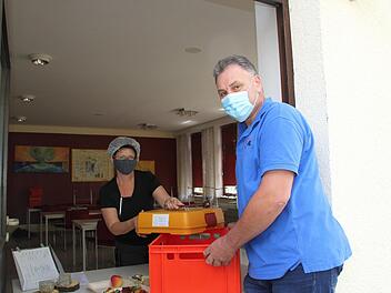 Isolde Ploner übergibt ein Menü in der Transportbox an Fahrdienstleiter Werner Hauck. Der Koordiniert den Lieferservice "Essen auf Rädern", den die Arbeiterwohlfahrt in Ebern nach wie vor anbietet. Fotos: Sven Dörr 