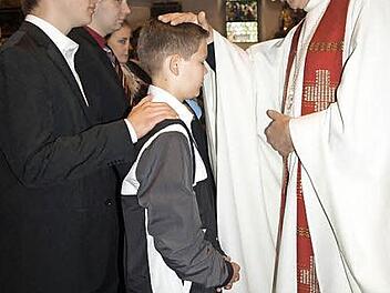 Christian Kuhnlein wird von Regionaldekan Thomas Teuchgräber gefirmt. Links sein Pate Max Hollendonner. Foto: Deuerling