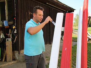 Fabian Nöth streicht gerade eine der beiden Sitzgelegenheiten, die demnächst als Mitfahrbänke dienen sollen. Die Farben hat er ausgewählt, weil sie für Franken stehen und er Rot und Weiß noch zu Hause  hatte. Thomas Malz