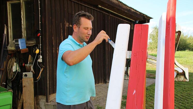 Fabian Nöth streicht gerade eine der beiden Sitzgelegenheiten, die demnächst als Mitfahrbänke dienen sollen. Die Farben hat er ausgewählt, weil sie für Franken stehen und er Rot und Weiß noch zu Hause  hatte. Thomas Malz