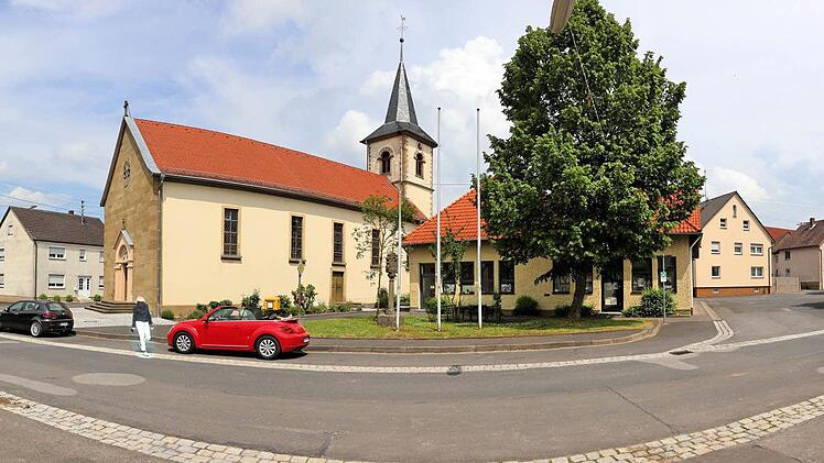 Der Dorfplatz in Seubrigshausen soll umgestaltet werden. Unten auf dem Bild die Kreisstraße 11, in der Mitte des Bildes Gemeindehaus mit der Bank und der Feuerwehr, links die Kirche St. Kilian. Foto: Dieter Britz