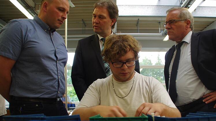 Michael Steiner (l.) erklärt am Beispiel von Manuel Renner (v.), wie die Arbeitsabläufe in den Wefa-Werkstätten funktionieren. CSU-Landratskandidat Klaus Löffler und Staatssekretär Johannes Hintersberger (r.) hören aufmerksam zu.
