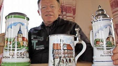 Franz Böhmer mit drei Bierkrügen, die heimatliche Motive aus Bad Staffelstein und seinem Heimatdorf Wiesen zeigen. Foto: Matthias Einwag
