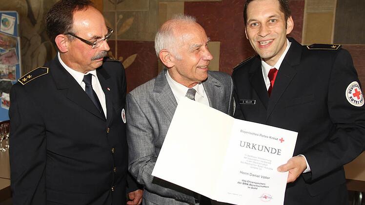 Kreisbereitschaftsleiter Udo Hoppe und Dr. Gerhard Beyer zeichnen Daniel Völler mit dem Ehrenzeichen in Gold aus.