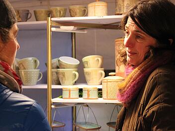 Töpferin Andrea Martini (rechts) aus Altdorf ist zum ersten Mal beim Weihnachtstöpfermarkt im Thurnauer Schloss dabei. Ihre mit einem Stempel bedruckten Arbeiten fanden großes Interesse. Foto: Katharina Müller-Sanke
