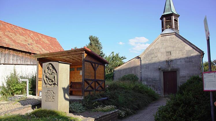 Der Platz wartet auf seine Umgestaltung. Wo jetzt das provisorische Buswartehäuschen auf der Löschwasserzisterne steht und in Richtung Kirche entsteht die neue Grünfläche, das Kriegerdenkmal bekommt einen neuen Platz und vor der Zisterne werden Brunnen, Bank und Baum zum Verweilen einladen.  Sabine Weinbeer