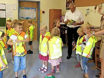 Die Erstklässler der Grundschule Trebgast haben die gelben Warnwesten gleich mal anprobiert. Lehrerin Ulla Eger und Erhard Eckert vom ADAC Nordbayern geben Hilfestellung. Foto: Dieter Hübner