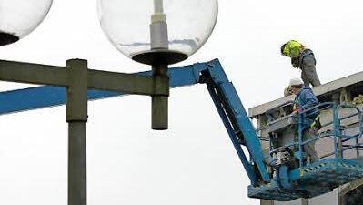 Zwei Arbeiter demontieren die Verblechung am Dach, die Betonteile sind schon entfernt worden.
