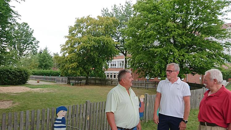 Georg Habermann, Ralf Olmesdahl und Josef Staudigel (von links) wollen sich nicht so schnell damit abfinden, dass das alte Aischer Schulhaus (im Hintergrund) abgerissen und auf dem Spielplatz (links) ein neuer Kindergarten gebaut werden soll.  Fotos: Andreas Dorsch