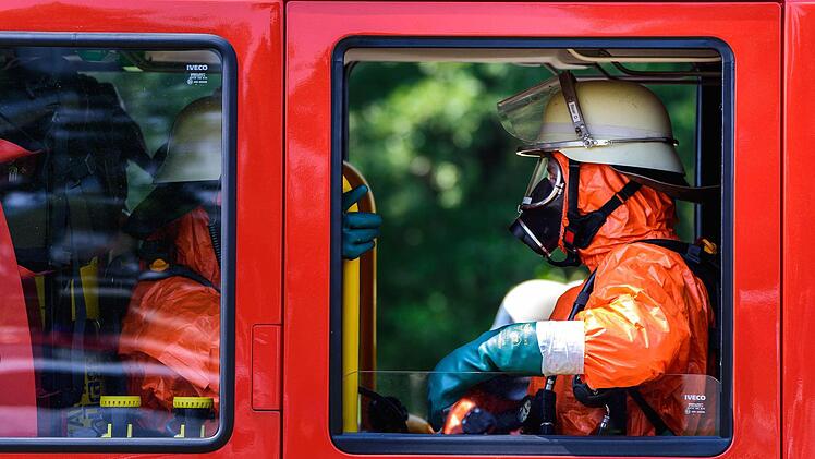 Einsatzkräfte der Feuerwehr mit Ganzkörper-Schutzanzügen sitzen am 11.08.2015 in Engelmannsreuth (Bayern) in einem Einsatzfahrzeug. Bei Engelmannsreuth ist ein F-16 Kampfjet der US-Streitkräfte abgestürzt. Foto: Nicolas Armer/dpa