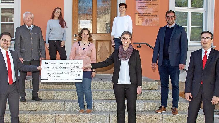 Viele der am eCn-Projekt beteiligten Personen waren dabei, als der symbolische Scheck über 8500 Euro übergeben wurde. Erste Reihe von links: Stefan Schneyer (Sparkasse), Dekanin Stefanie Ott-Frühwald, Markus Engel (Sparkasse), 2. Reihe v.l.: Helmut Fischer (stellvertretender Landrat), Lena Stahn (Sozialpädagogin), Dirk Rosenbauer (Bürgermeister), 3. Reihe v.l.: Christina Kuntz (Agentur für Arbeit), Susanne Fleuchaus (Schulkindbetreuung im Dekanat Michelau)  Foto: Klaus Gagel